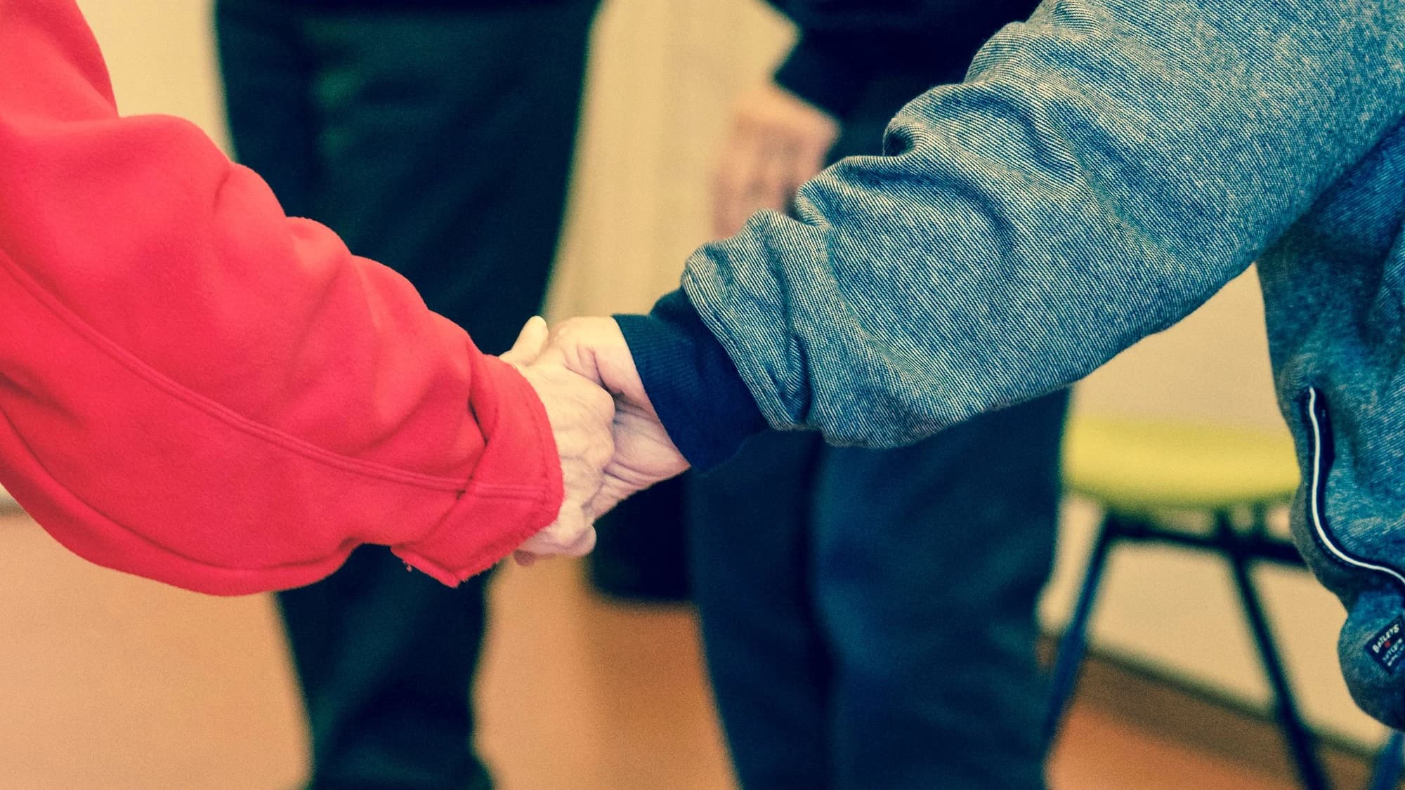 Older adult's hands wrapped in a younger person's hands.