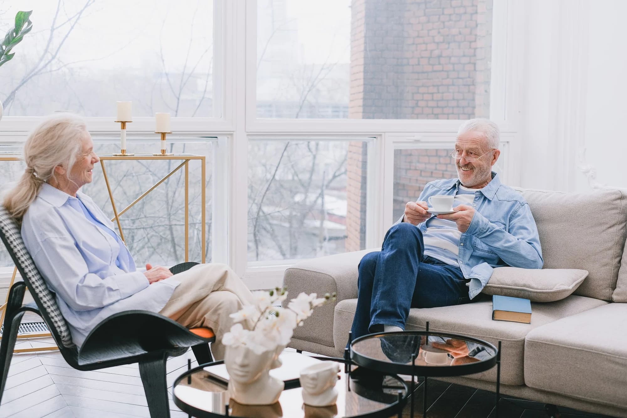 Two people sharing tea and conversation in a sunlit kitchen.