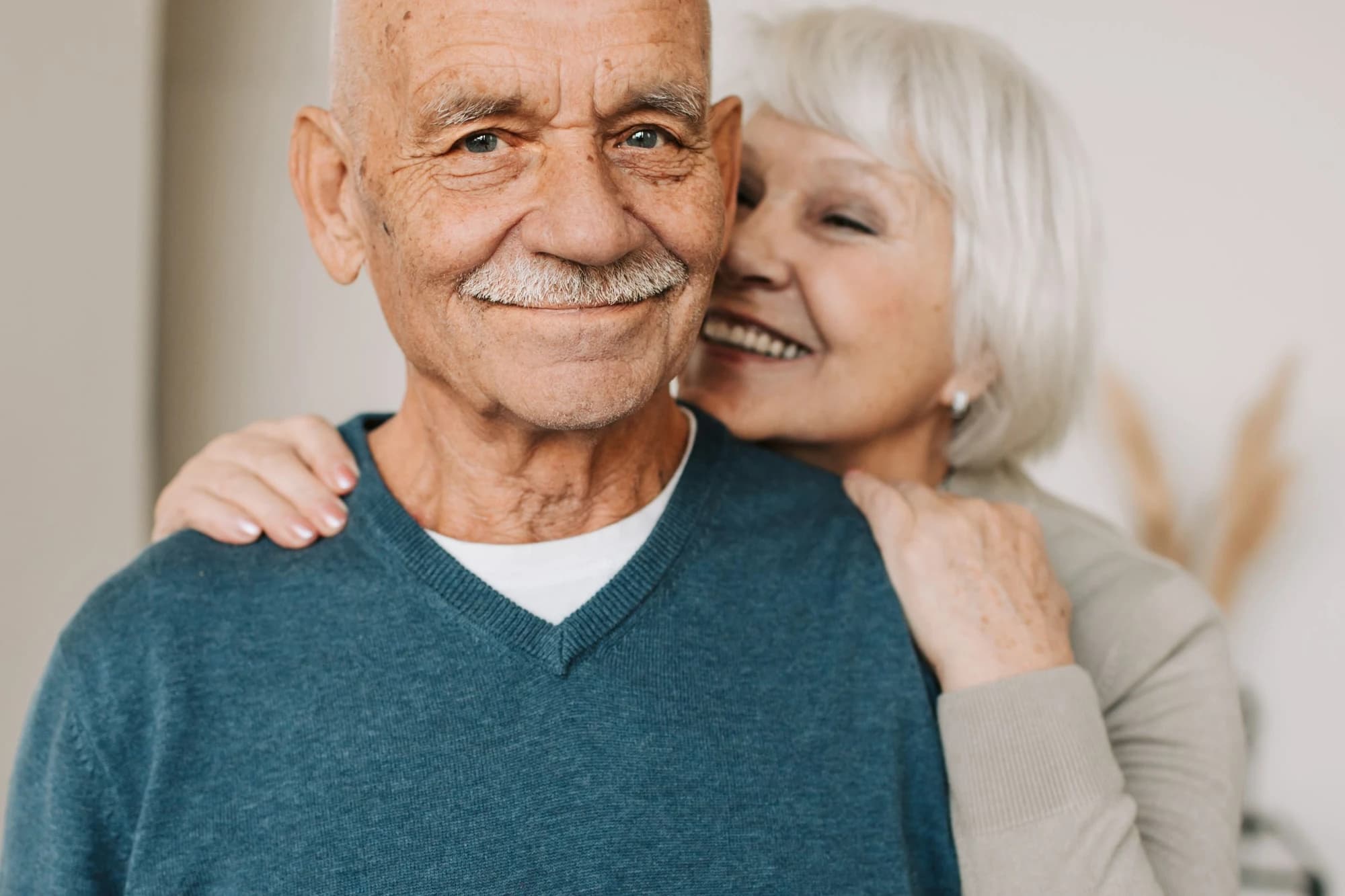 A senior couple embrace warmly, a portrait of the lives our team helps hold together.