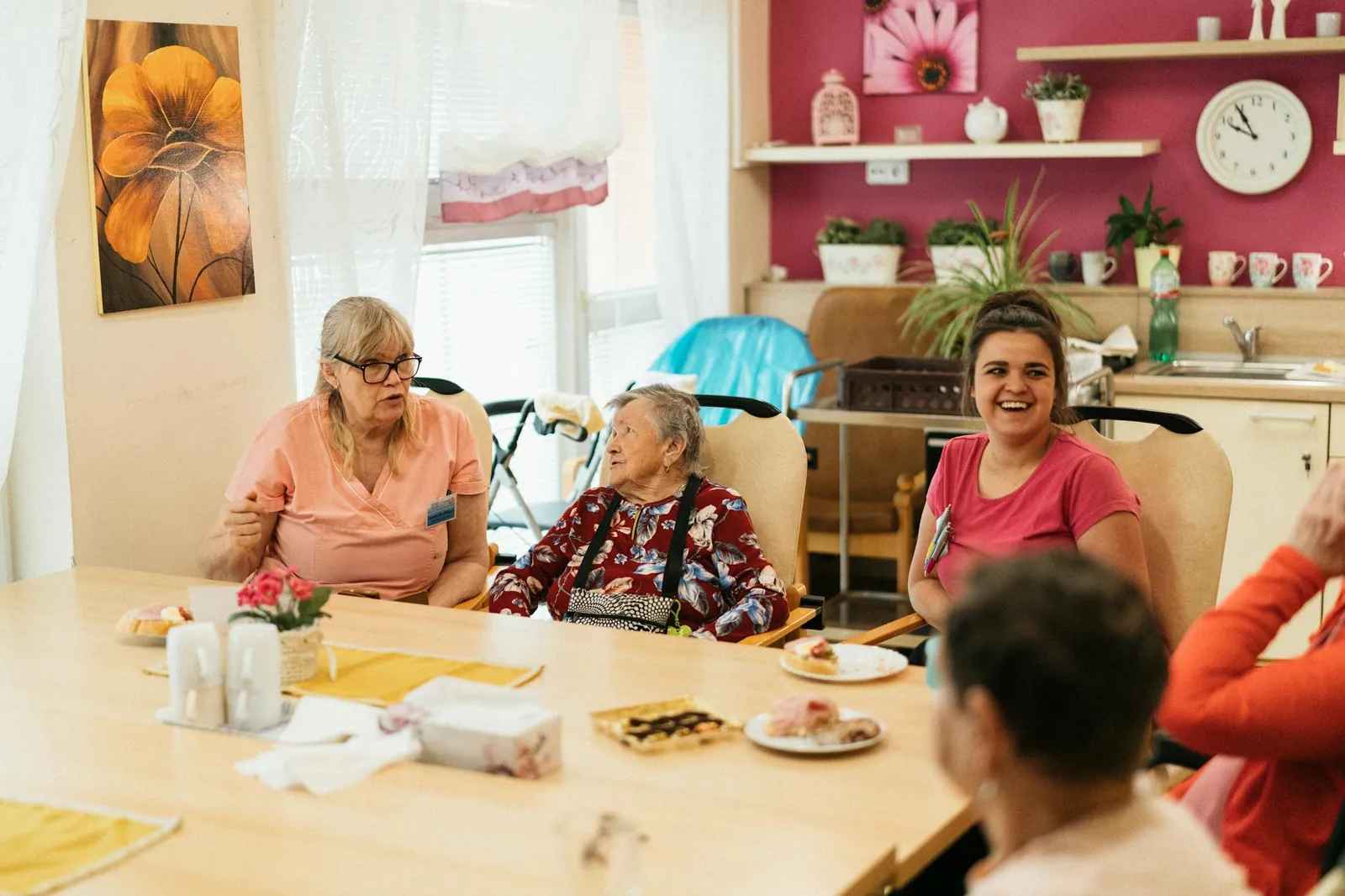 Polaris Gateway carers and the people they support share a meal at a sunlit table.